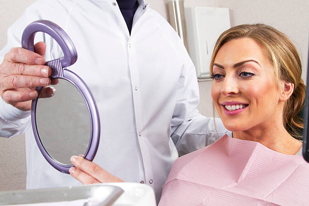 Dental patient smiles in mirror with dental bib